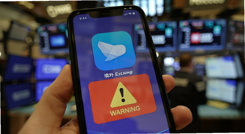 手机屏幕上显示境外交易所App与警告标识图