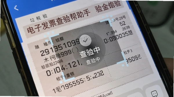 电子发票查验帮手app的扫码界面实拍,手机对准一张增值税发票,屏幕上弹出“查验中”动画,旁边显示已识别的发票号码和校验码。